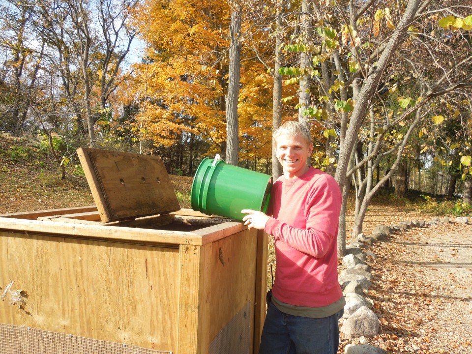 Jonathan Fiedley putting compost in the staff-made compost box at Camp Friedenswald