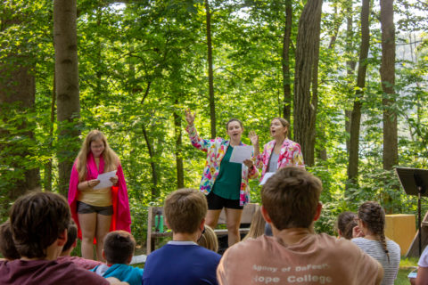 people performing and others watching in the woods