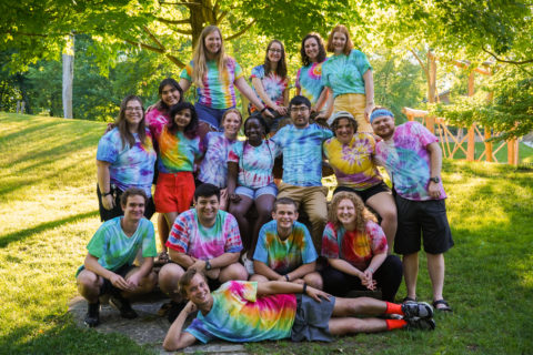 A group photo of Camp Friedenswald's 2022 summer staff, all wearing tie dye shirts.
