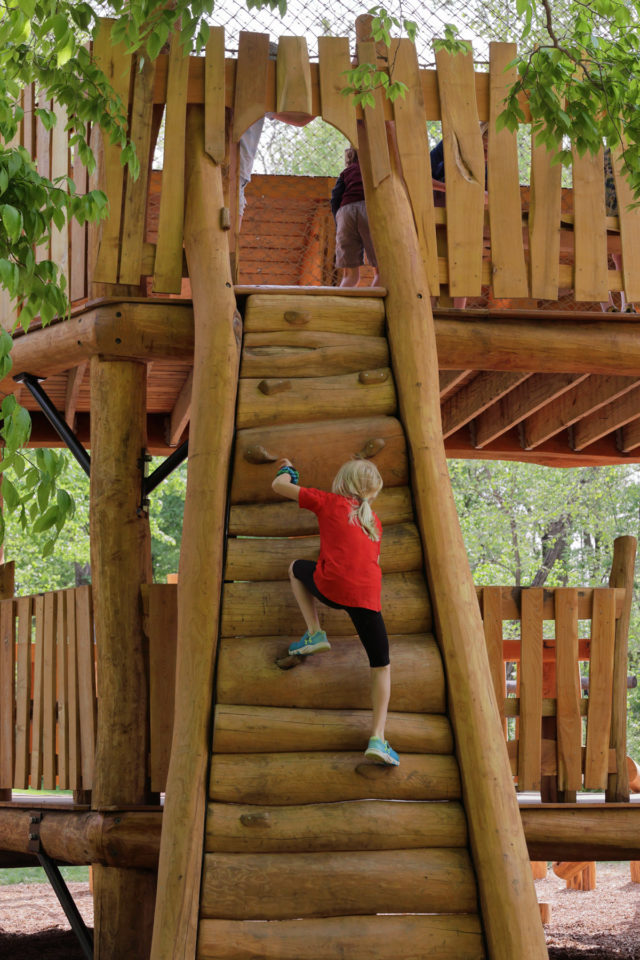 Child climbing up wooden climbing wall