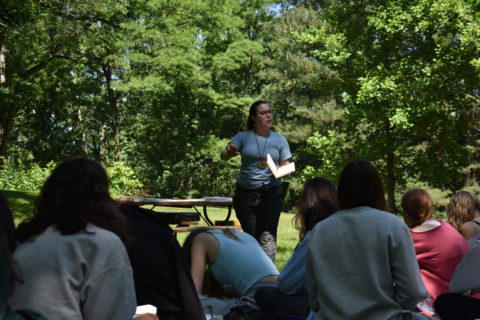 Woman standing in front of campers speaking